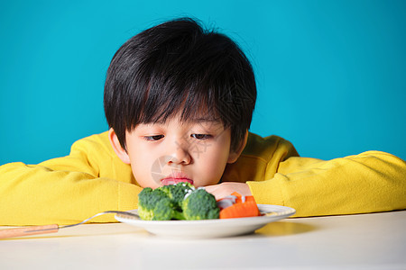 盯着蔬菜发愁的小男孩背景图片