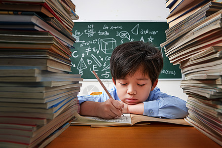 拿着铅笔的男孩疲劳的小学生写作业背景