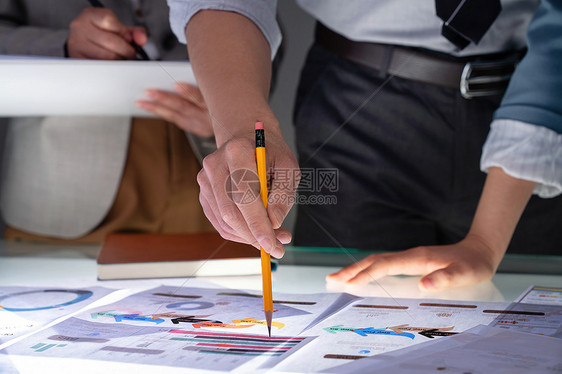 商务人士拿着铅笔指着报表分析研究图片