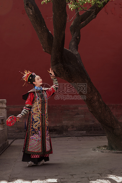 穿清宫服的青年女人站在古树下图片