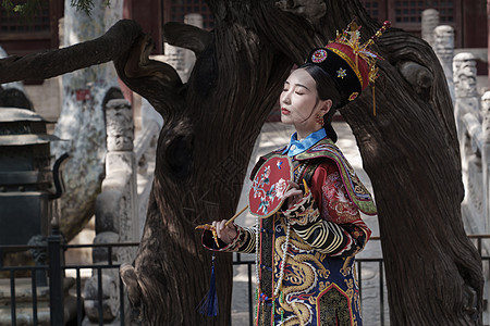 穿清宫服的青年女人站在古树下图片