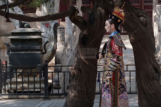 穿清宫服的青年女人站在古树下图片