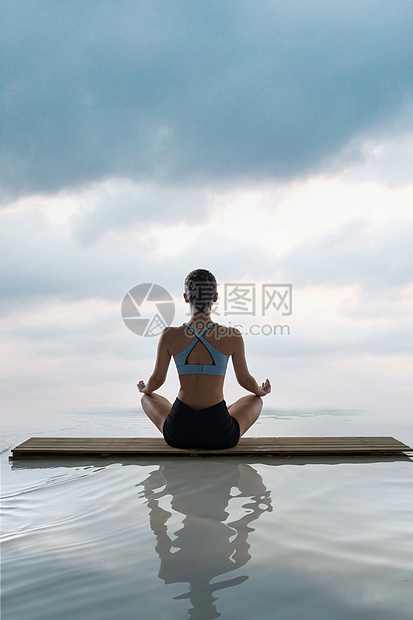 年轻女人在水面上练习瑜伽图片