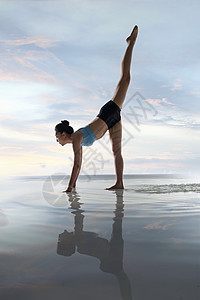 年轻女人在水面上练习瑜伽图片