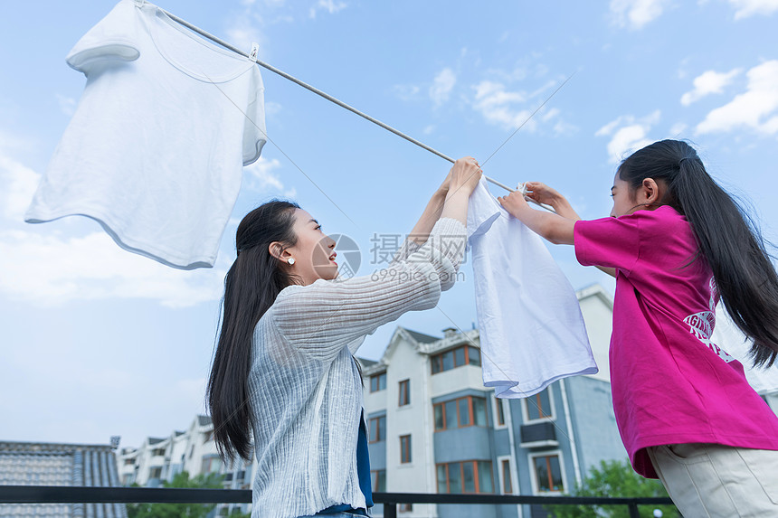 年轻妈妈和女儿晾衣服图片