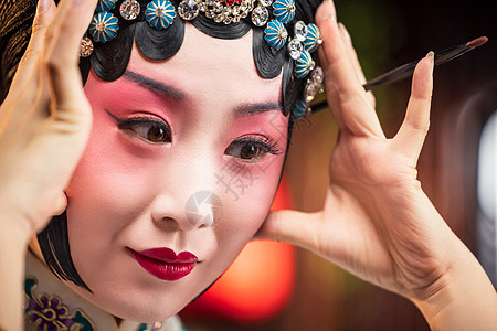 京剧女演员对着镜子佩戴首饰图片