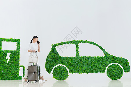 商务女士推着行李箱走在电动汽车旁图片