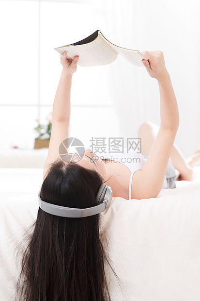 青年女人在卧室的床上听音乐图片