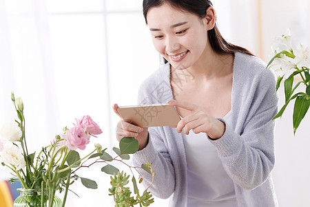 青年女人为鲜花拍照图片