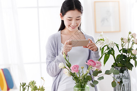 青年女人为鲜花拍照图片