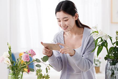 青年女人为鲜花拍照图片