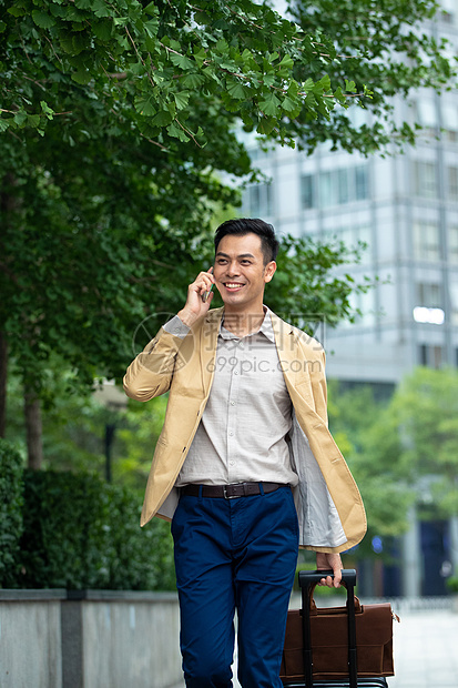 户外拉着行李打电话的商务男子图片