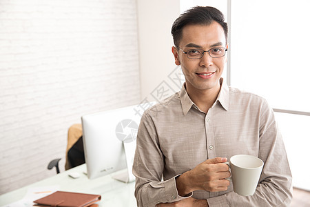 办公室内拿着杯子的商务男士图片