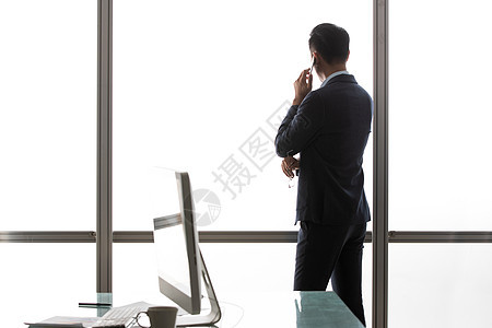 商务男士在窗户前打电话的背影图片