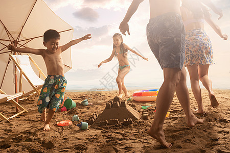 快乐的四口之家在沙滩上玩耍图片
