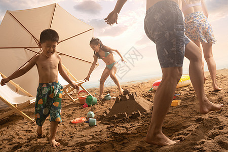 快乐的四口之家在沙滩上玩耍图片