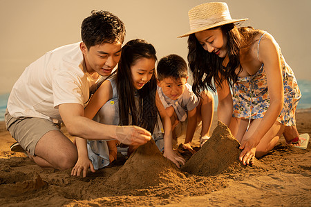 快乐的四口之家在沙滩上玩沙子高清图片