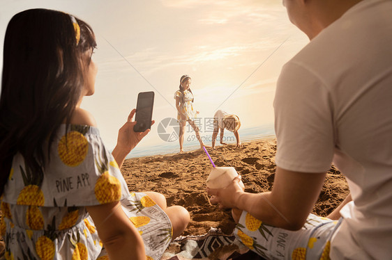 沙滩上青年夫妇为孩子拍照图片