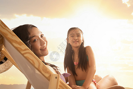 坐在沙滩椅上的年轻妈妈抱着女儿图片
