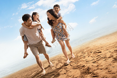 幸福的一家四口在沙滩上散步图片