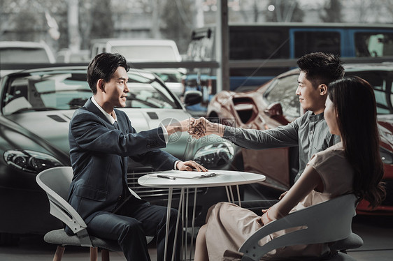 汽车销售人员和青年夫妇握手图片