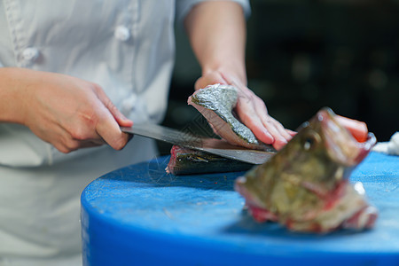 厨师使用菜刀将鱼切菱形刀段图片