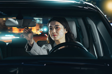 夜晚驾驶汽车的青年女人调整后视镜图片