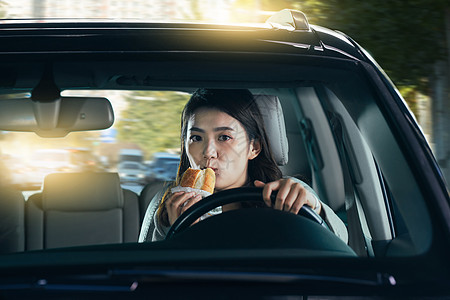 驾驶汽车的青年女人吃食物图片