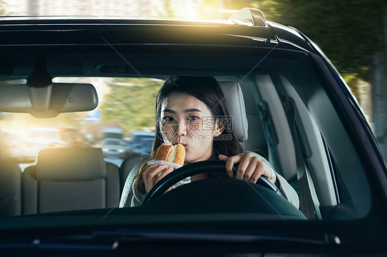 驾驶汽车的青年女人吃食物图片