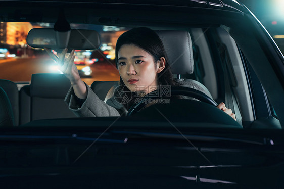 夜晚驾驶汽车的青年女人调整后视镜图片