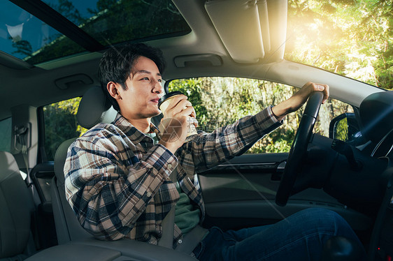 驾驶汽车的青年男人喝咖啡图片