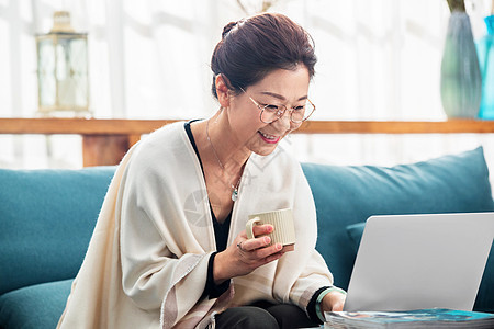 优雅的中老年女士在家使用笔记本电脑图片