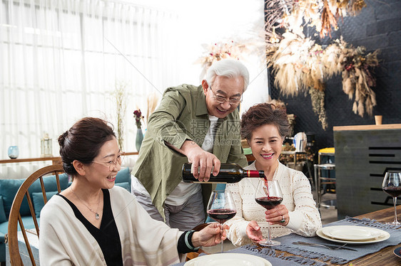 聚会上老年男人给朋友们倒红酒图片