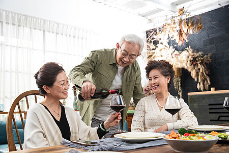 聚会上老年男人给朋友倒红酒图片