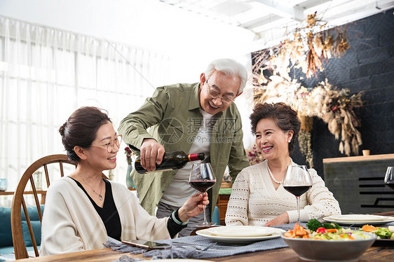 聚会上老年男人给朋友倒红酒图片