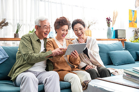 快乐的老年人坐在沙发上一起使用平板电脑图片
