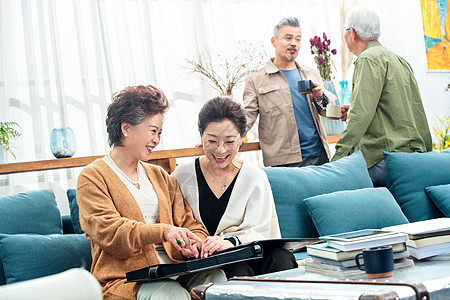 快乐的中老年人们在居室喝茶聊天看相册图片