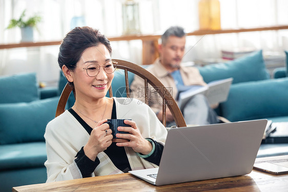 中老年女士在家捧着杯子看笔记本电脑图片