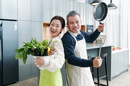 平底锅铲子快乐的中老夫妇在厨房做饭背景
