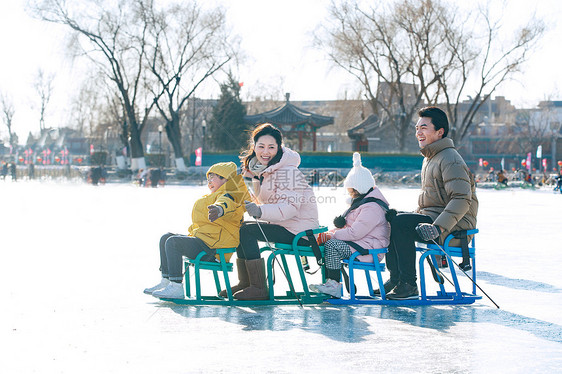 快乐的一家四口坐冰车玩耍图片