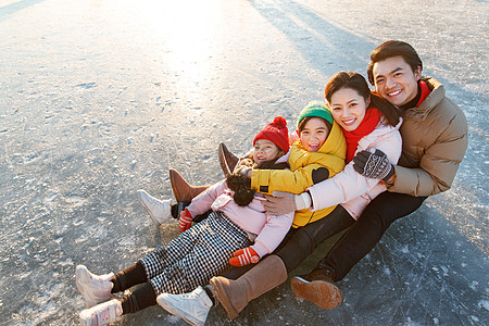 冬奥会快乐的一家四口坐在冰面上玩耍背景
