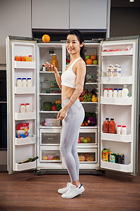 穿着运动装的青年女人站在冰箱前图片