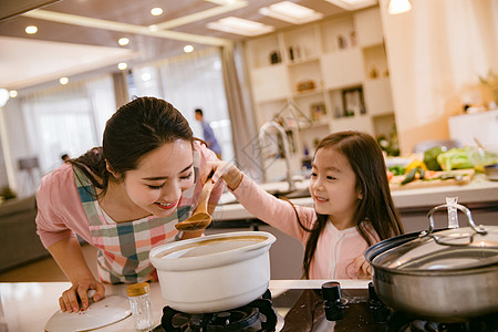 做饭的妈妈年轻妈妈和女儿在厨房背景