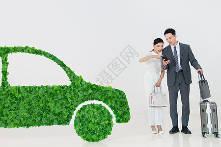 青年夫妇推着行李箱走在电动汽车旁图片