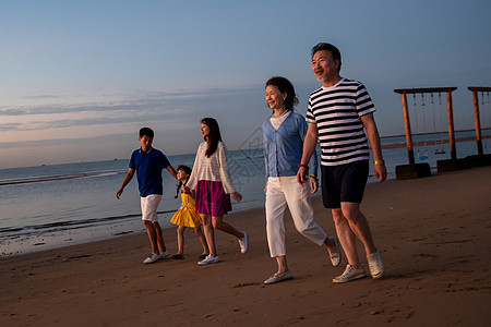 夕阳下在海边散步的幸福家庭图片