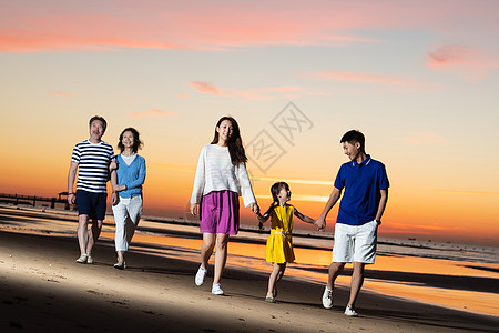 夕阳下在海边散步的幸福家庭图片