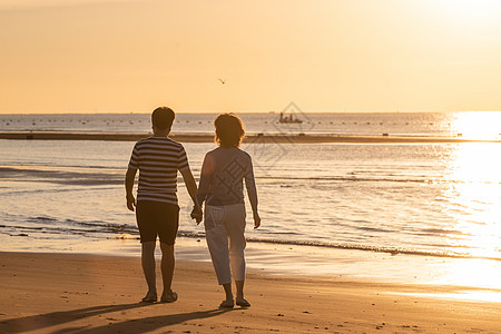 海滩晚霞老年夫妇在海边散步背景