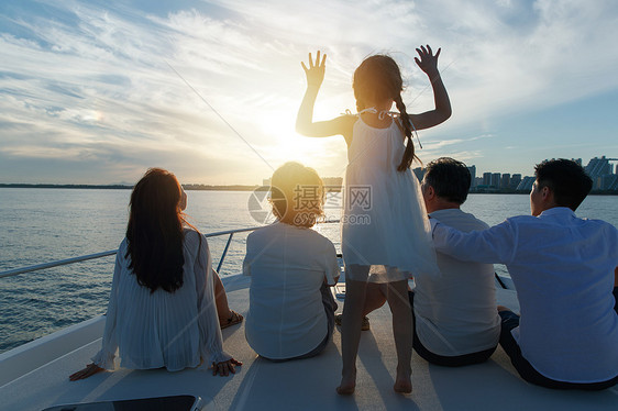 夕阳下坐在游艇上的快乐一家人图片