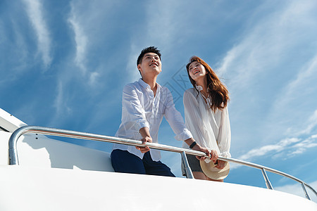 游艇情侣浪漫的青年夫妇乘坐游艇出海背景