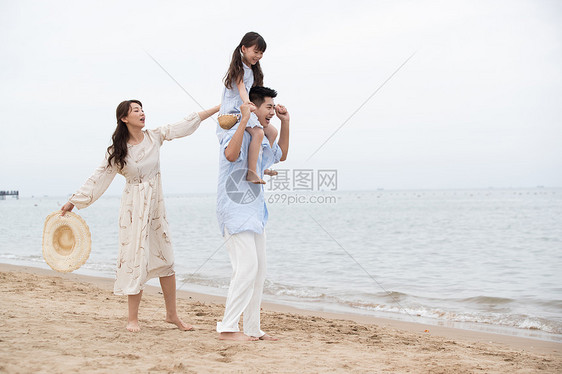 幸福的一家三口在海边玩耍图片